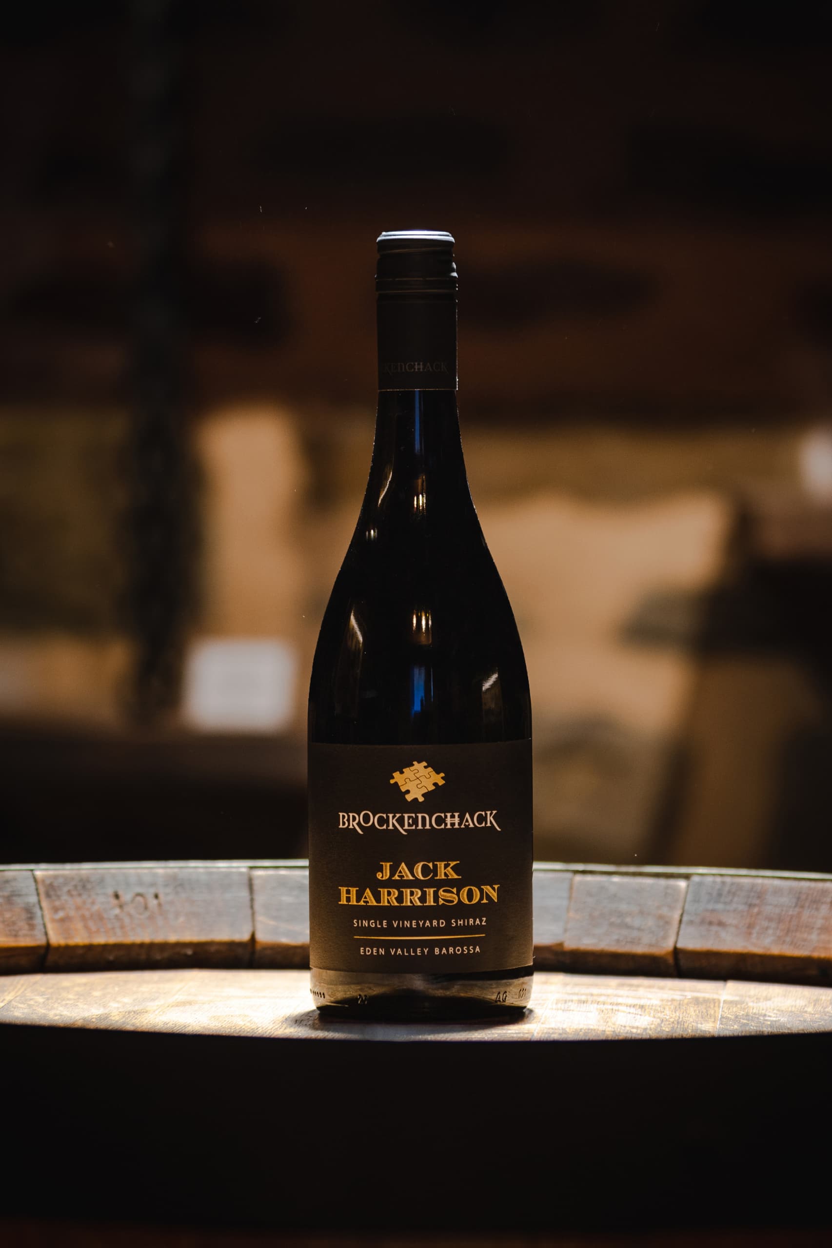 A bottle of Jack Harrison single vineyard Shiraz from Brockenchack Wines sitting on a wine barrel