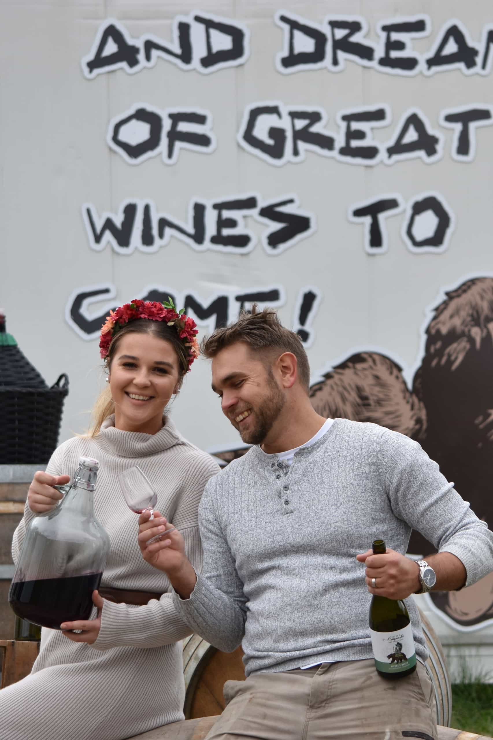 Natalia and Artur Krupinski sitting side by side holding wine at their cellar door